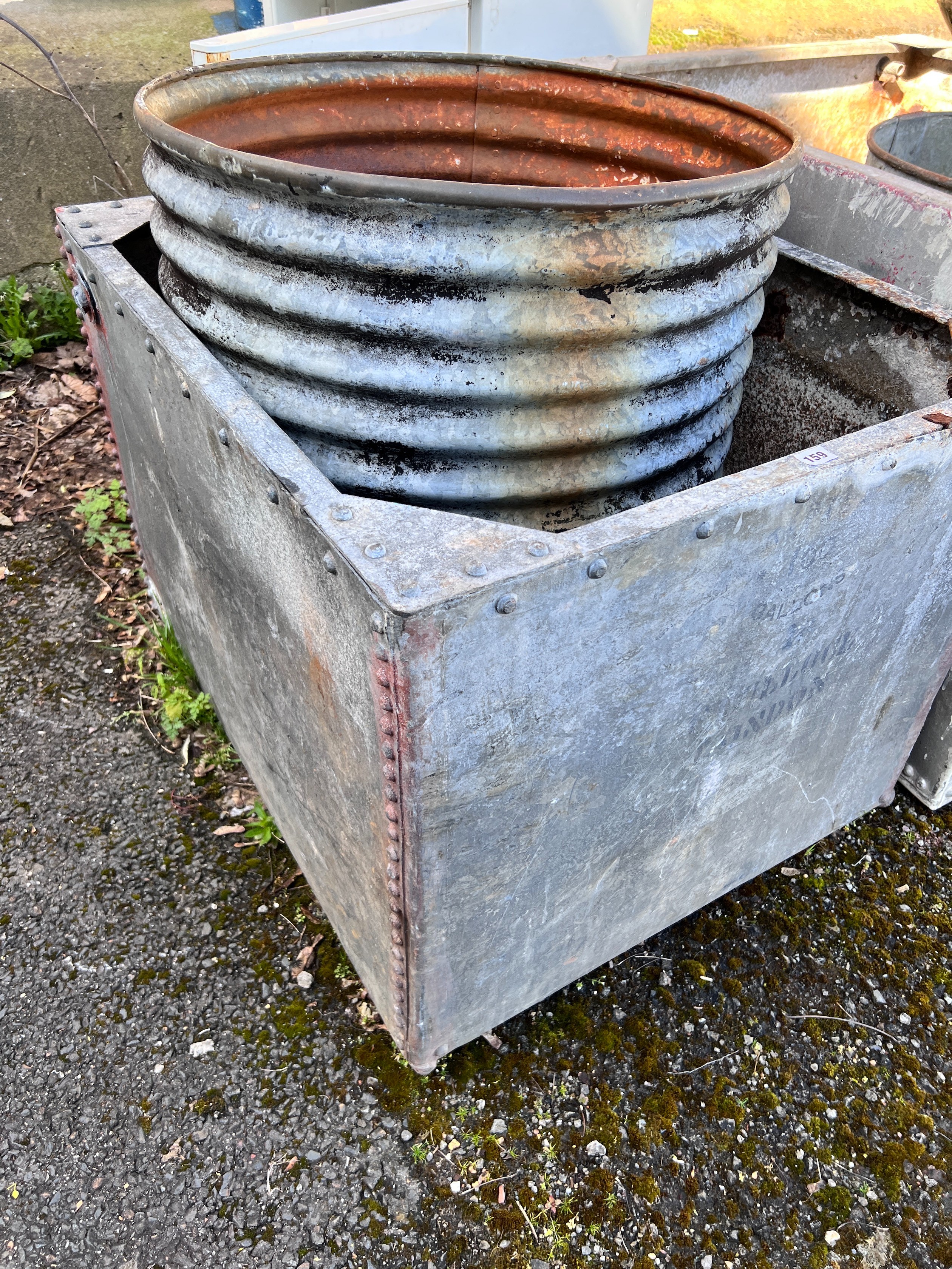 A large rectangular galvanised tank, width 90cm, depth 76cm, height 64cm together with a circular galvanised tank *Please note the sale commences at 9am.